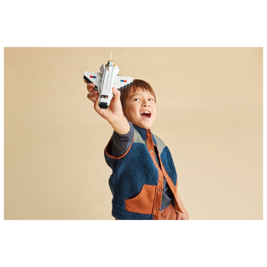 Niño sonriente jugando con el transbordador espacial LEGO armado