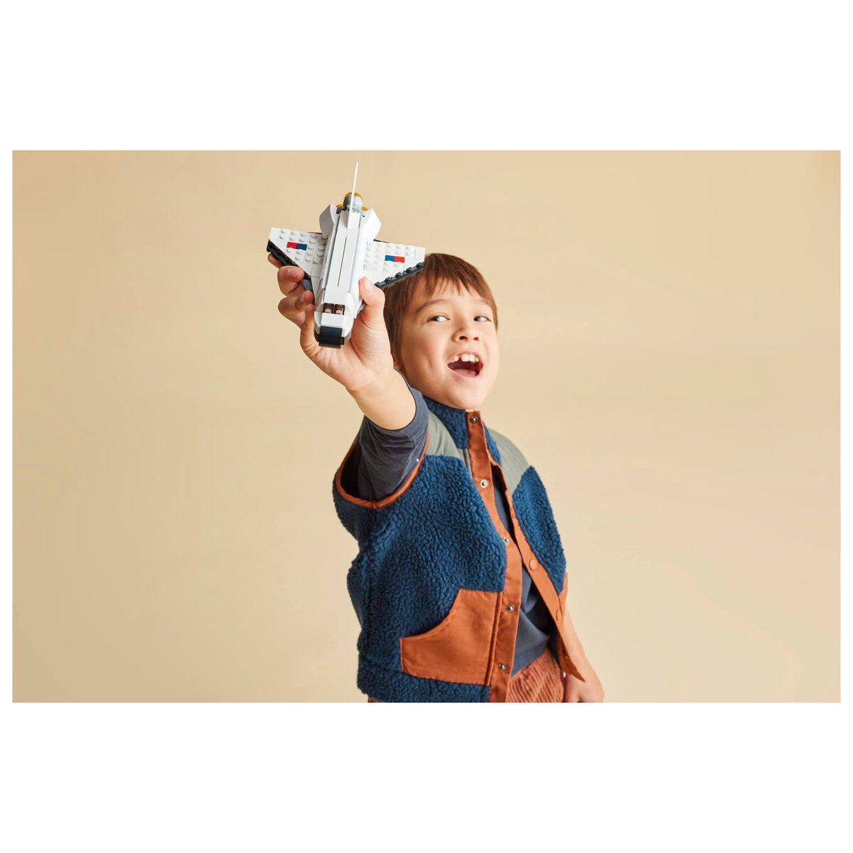 Niño sonriente jugando con el transbordador espacial LEGO armado