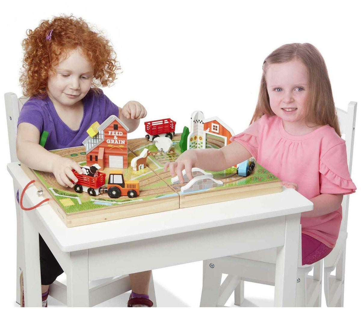 Dos niñas jugando con la granja de madera Take-Along Farm sobre una mesa