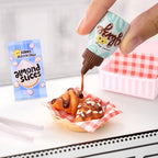 Mano decorando croissants en miniatura con salsa de chocolate Miniverse