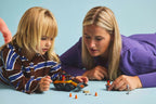 Niña y adulta jugando con la cargadora LEGO City en el suelo