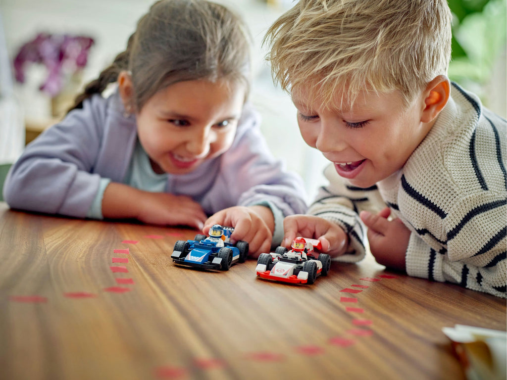 Niños jugando carreras con los autos LEGO de Williams y Haas sobre una mesa