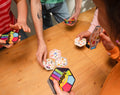 Manos poniendo cartas hexagonales de Dobble Connect sobre la mesa