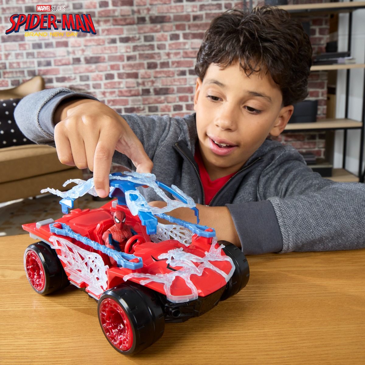 Niño jugando con el buggy de Spider-Man sobre una mesa