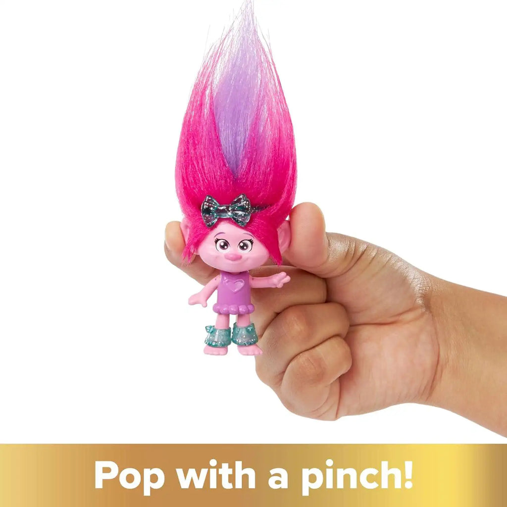 Muñeca Poppy de Trolls con pelo rosado y lila en la mano de una niña