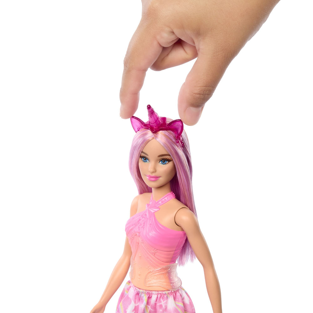 Mano colocando el cintillo de unicornio en la cabeza de la Barbie