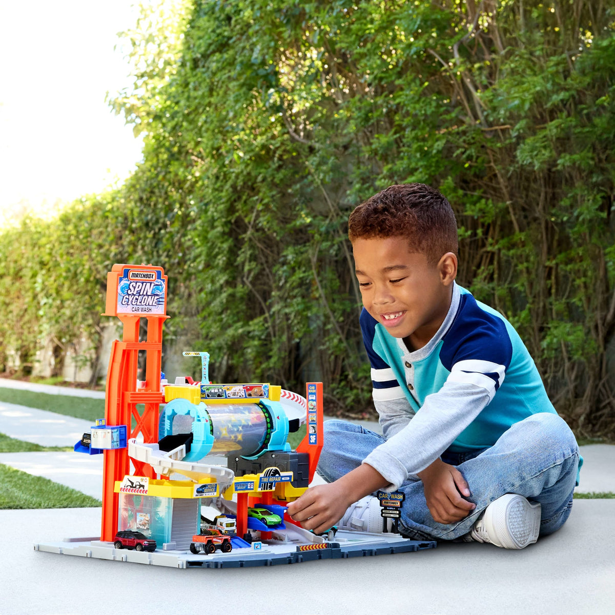 Niño jugando con el autolavado Matchbox de varios pisos en el patio