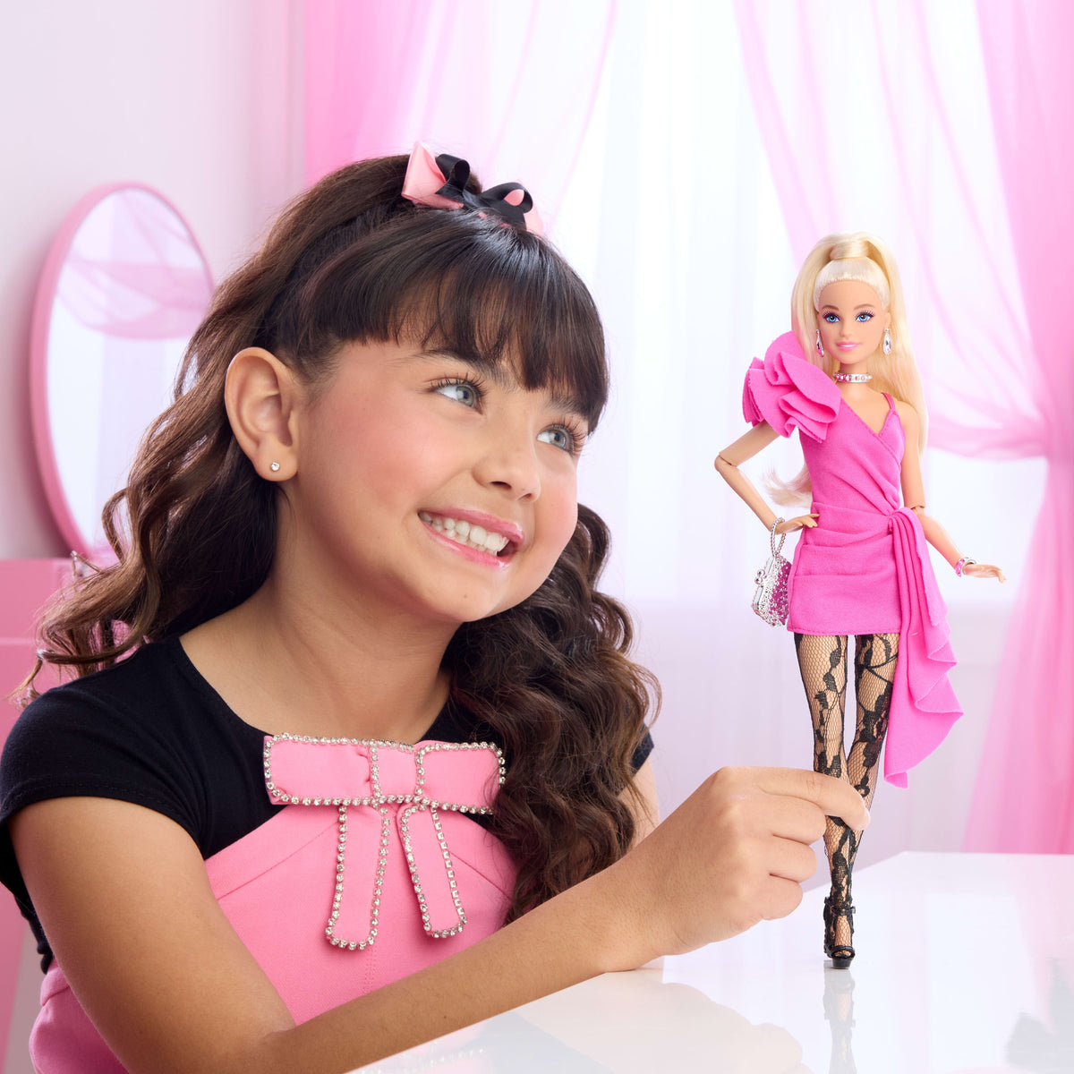 Niña sonriendo mientras juega con la Barbie Deluxe Style fucsia