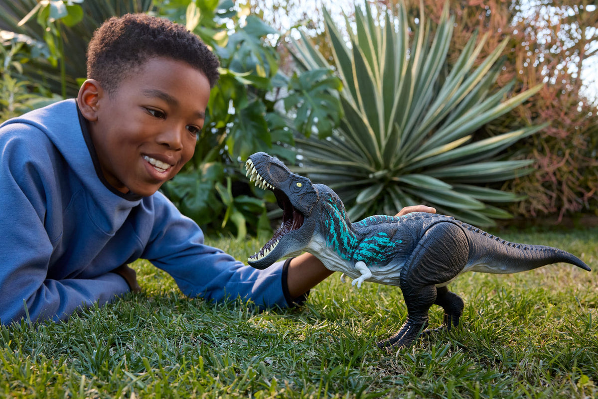 Niño jugando con el T-Rex Jurassic World sobre el pasto