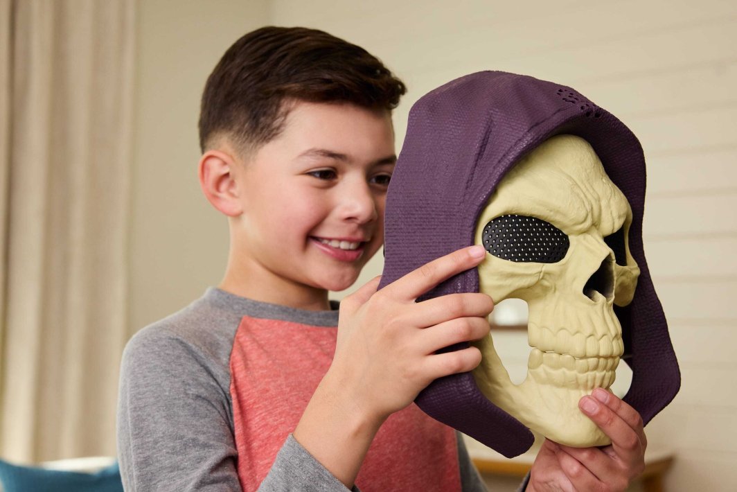 Niño sosteniendo la máscara de Skeletor con capucha morada