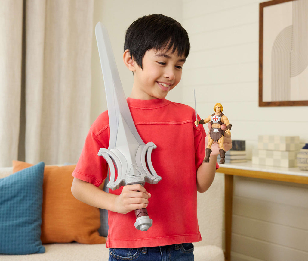 Niño sosteniendo la Espada del Poder junto a una figura de He-Man