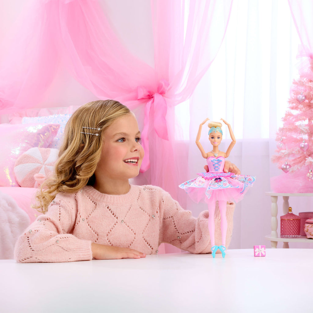 Niña jugando con la muñeca Barbie Clara en pose de ballet en una sala rosada