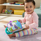 Niña sentada en el suelo jugando con el libro Cuentos y Rimas abierto