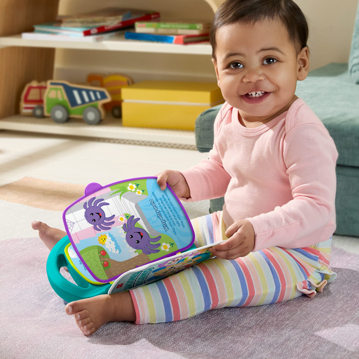 Niña sentada en el suelo jugando con el libro Cuentos y Rimas abierto