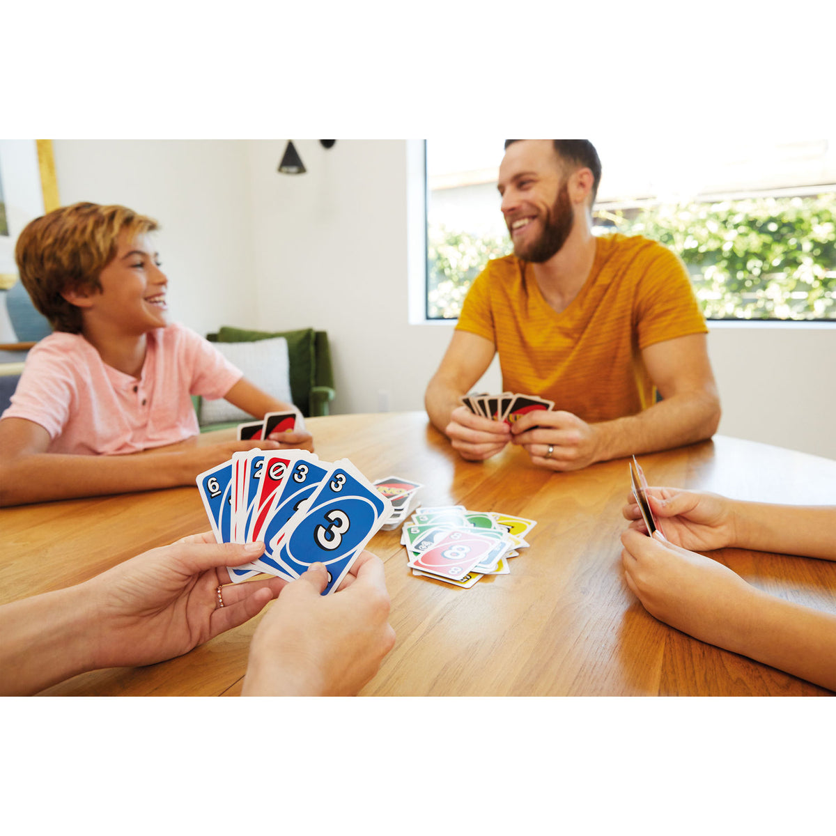 Familia jugando UNO en la mesa del comedor